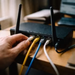 Hand plugging ethernet cable into home router rear panel for gaming port forwarding setup