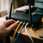 Hand plugging ethernet cable into home router rear panel for gaming port forwarding setup